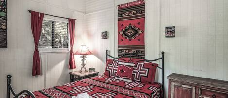 Quarto bem arrumado com cama, mesa de cabeceira, abajur e cômoda.