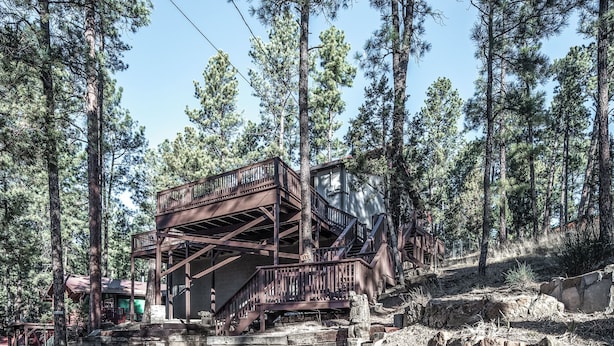 A wooden cabin with a balcony, surrounded by tall pine trees. - A Climbing Cub by Ruidoso Vacation Rentals (Ruidoso)