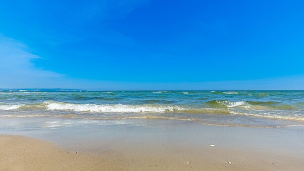 Una spiaggia con cieli azzurri e onde.