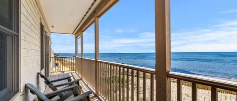 A covered porch with a view of the ocean.