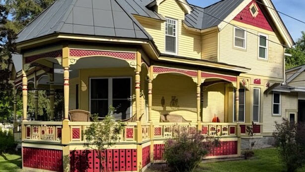 Een huis met twee verdiepingen, een overdekte veranda en een puntige daklijn.