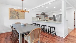Une cuisine moderne dotée d’un îlot central, de revêtements de sol en bois et d’un coin repas avec une grande table et des chaises.