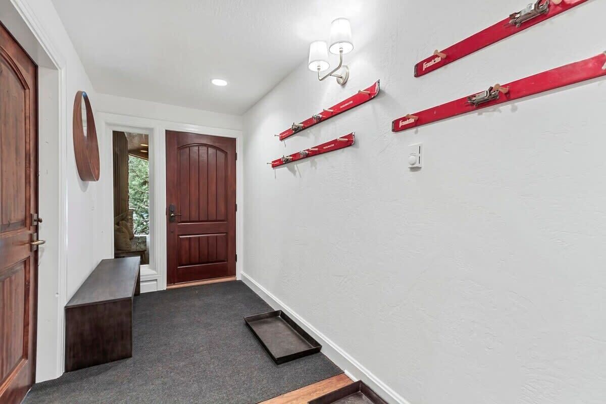 A hallway with a wooden bench, a door, and a wall-mounted light fixture.