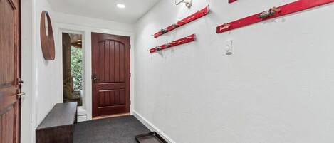 A hallway with a wooden bench, a door, and a wall-mounted light fixture.