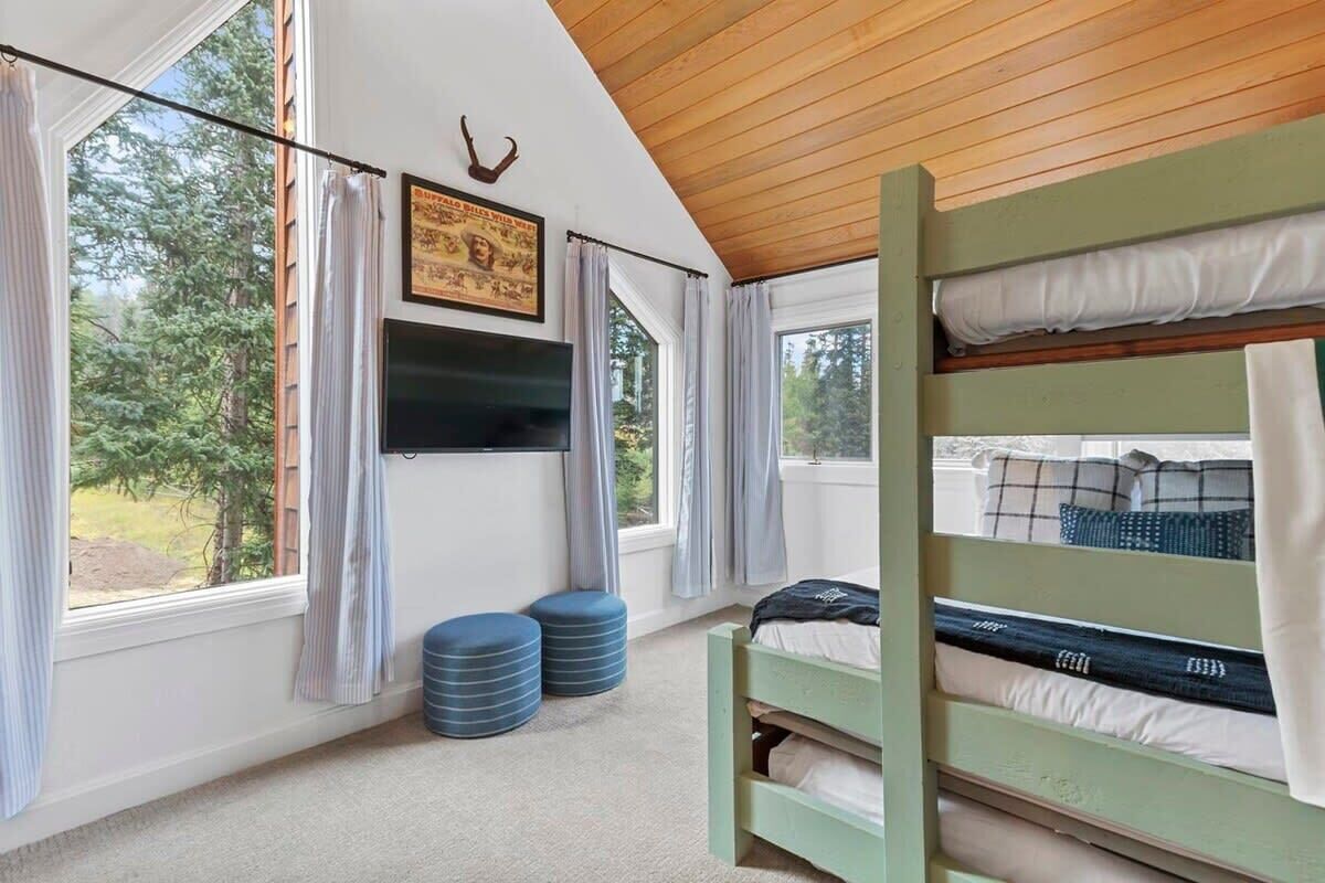 A bunk bed room with a television, curtains, and a framed picture on the wall.