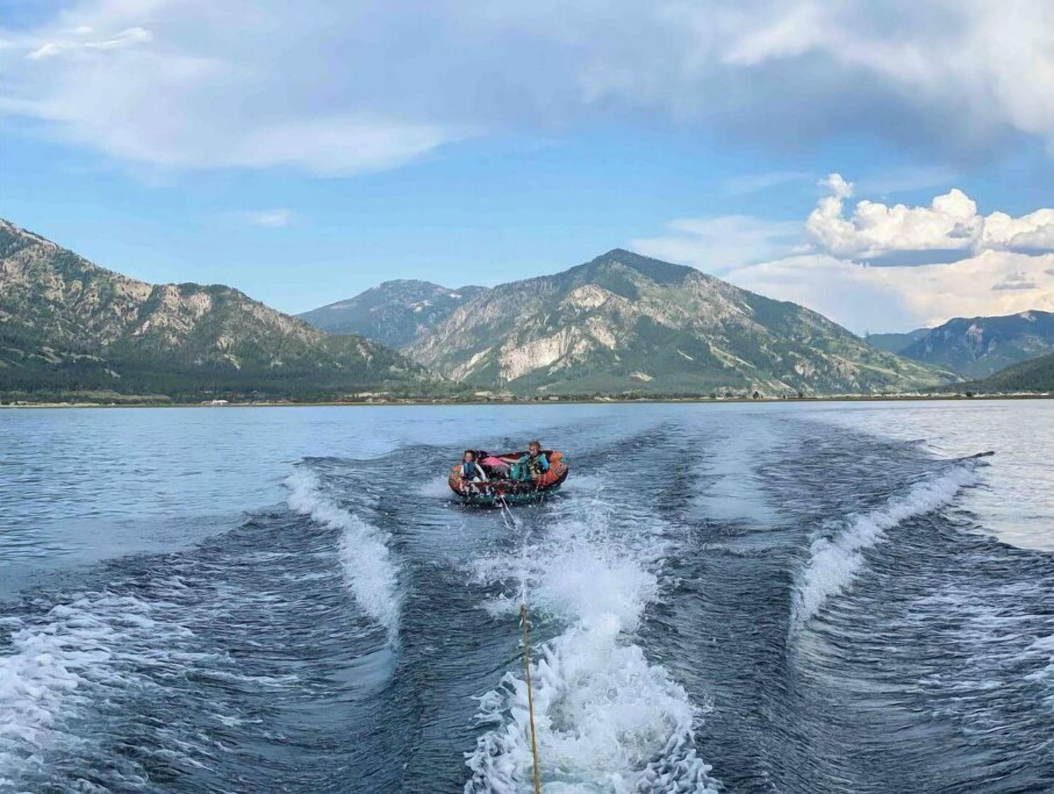 Ein Boot fährt über einen See, im Hintergrund Berge.