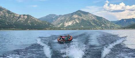 Un bateau navigue sur un lac, avec des montagnes en arrière-plan.