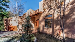 A modern house with a unique architectural style, featuring a large window and a well-maintained front yard with a small tree and rocks. - Casa Escondida by Ruidoso Vacation Rentals (Alto)