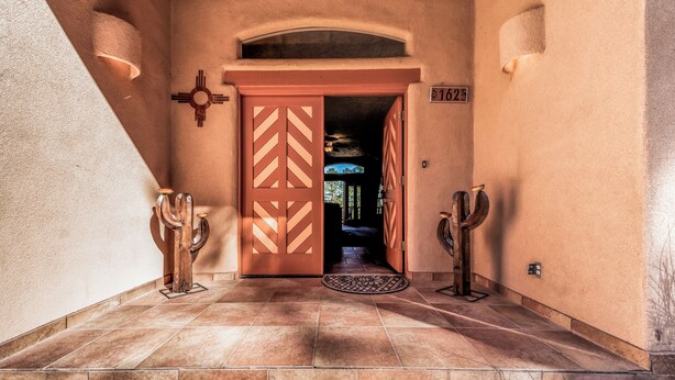 A hallway with a red door, a number plaque, and a small rug. - Casa Escondida by Ruidoso Vacation Rentals (Alto)