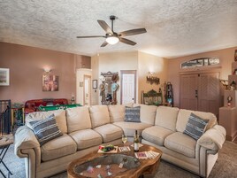 Un amplio salón con un sofá modular, una mesita de centro y un ventilador de techo.