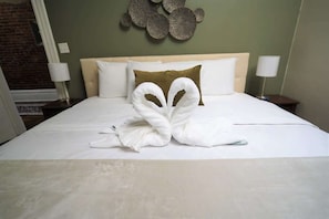 Una cama bien hecha con un original arreglo de toallas, un cabecero y un adorno de pared.