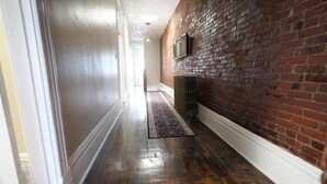 A hallway with wooden flooring, a brick wall, and a radiator. - *Historic Gem* Heart of Southside-Sleeps 10 (Pittsburgh)