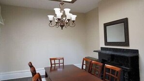 A dining room with a large wooden table, six chairs, a chandelier, a fireplace, and a skylight. - *Historic Gem* Heart of Southside-Sleeps 10 (Pittsburgh)