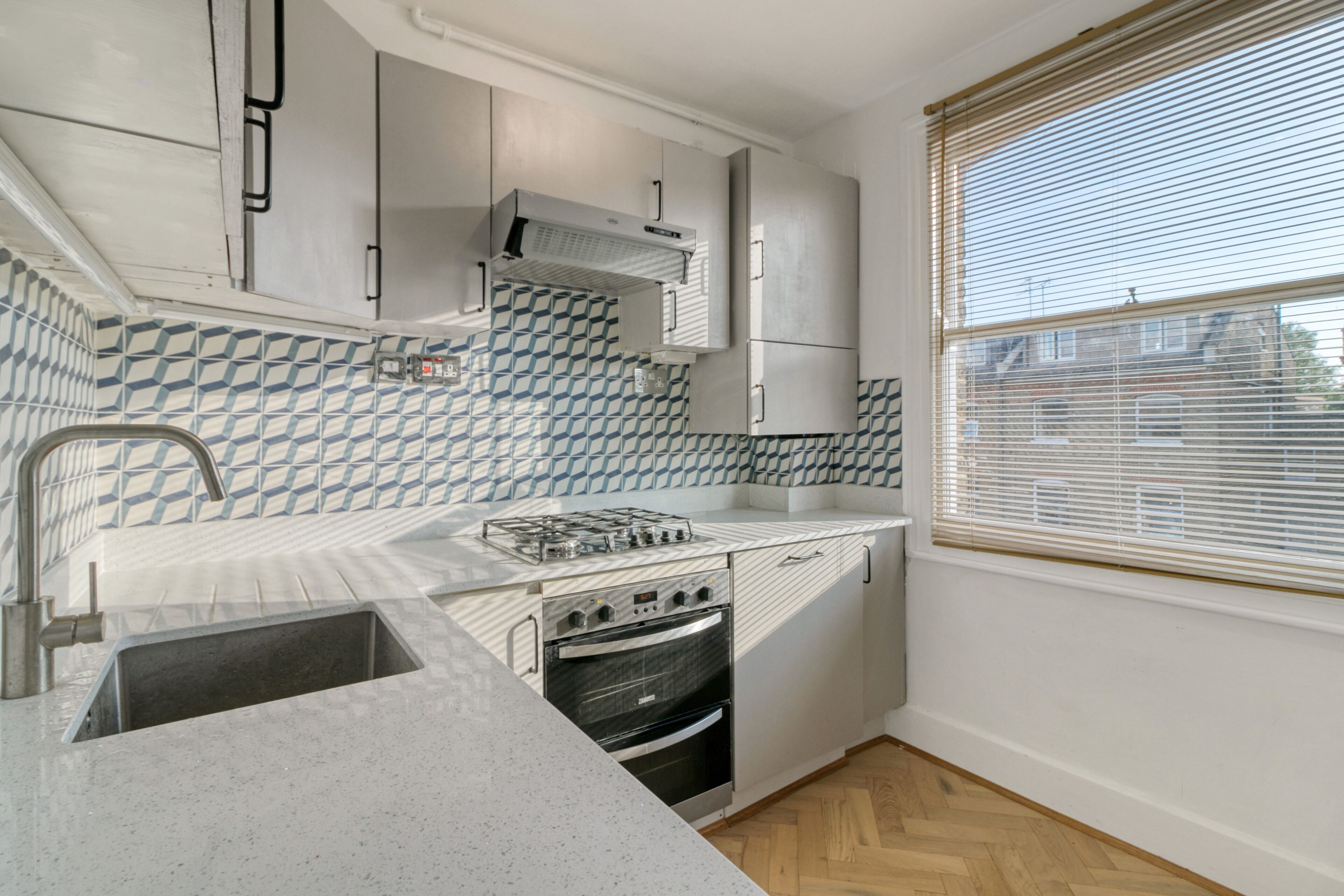 A compact kitchen with a gas stove, oven, and stainless steel sink.