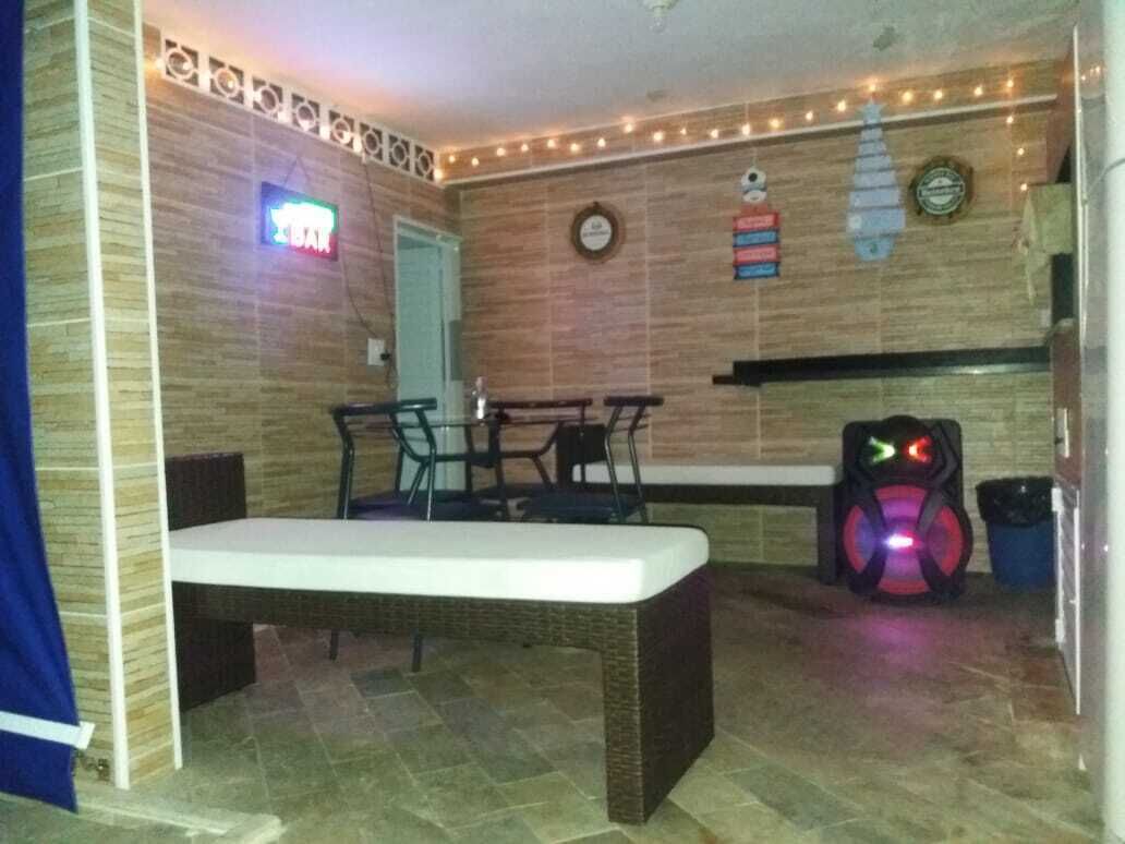 A room with a bench, a table, chairs, a neon sign, a clock, and a wall-mounted shelf.