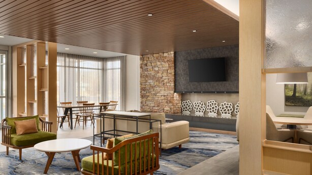 A spacious lobby with a stone wall, a flat-screen TV, and a seating area with chairs and a sofa. - Fairfield Inn & Suites By Marriott Rockaway (Rockaway)