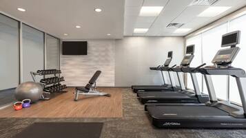 A gym with treadmills, dumbbells, and exercise balls.