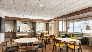 A modern restaurant interior with wooden flooring, round tables, and yellow chairs. - Fairfield Inn & Suites By Marriott Rockaway (Rockaway)