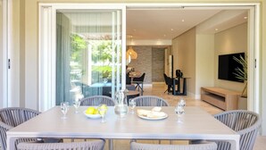 Un comedor con una mesa dispuesta para cuatro personas, sillas y vistas al jardín a través de un ventanal.