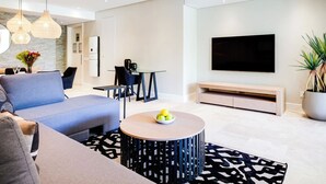 Una sala de estar moderna con un sofá, una mesa de centro, un televisor y un comedor con sillas y una mesa.