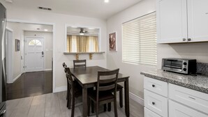 A modern kitchen with white cabinets, a granite countertop, and a built-in toaster.