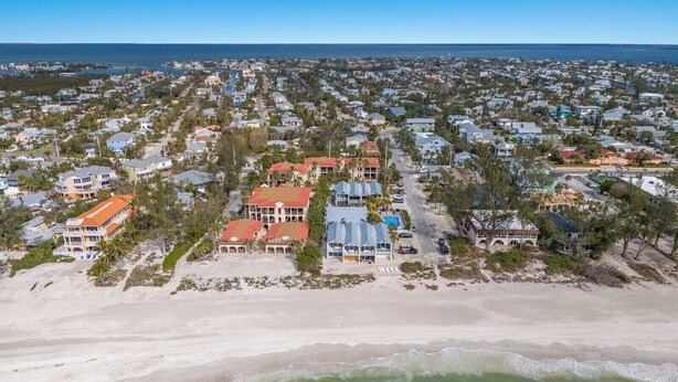 Vista aérea de una zona residencial costera con casas, una playa y una vista despejada del océano.
