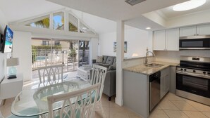 Una cocina moderna con armarios blancos, un horno de acero inoxidable y una mesa de vidrio con sillas.
