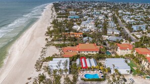 Vista aérea de una zona residencial costera con casas, una playa y una piscina.