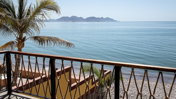 Un balcon offrant une vue sur une mer calme et des montagnes lointaines.