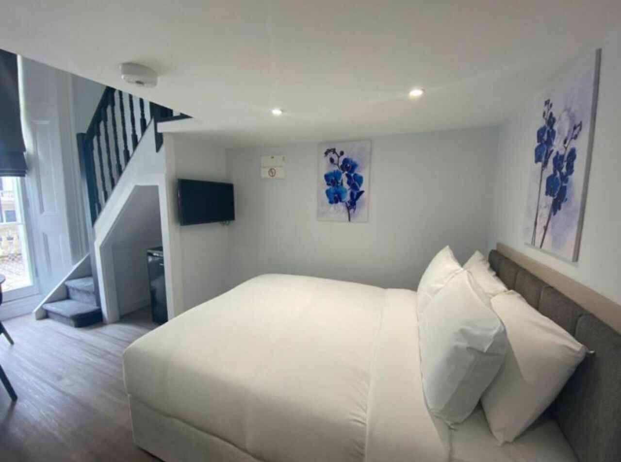 Een slaapkamer met een groot bed, een trap en een flatscreen televisie aan de muur.