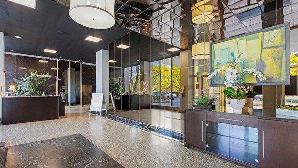 Eine moderne Lobby mit einer Rezeption, Glastrennwänden und einem großen abstrakten Gemälde.