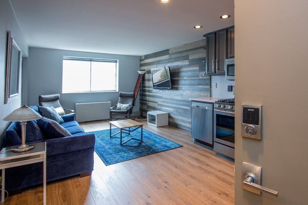 A modern living room with a blue sofa, a coffee table, and a TV on a wooden wall.