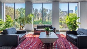 Ein modernes Wohnzimmer mit großem Fenster, einer Couch, einem Couchtisch und Topfpflanzen.