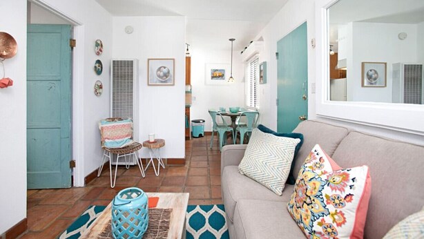 Una sala de estar acogedora con un sofá, una mesa de comedor y una zona de cocina al fondo.