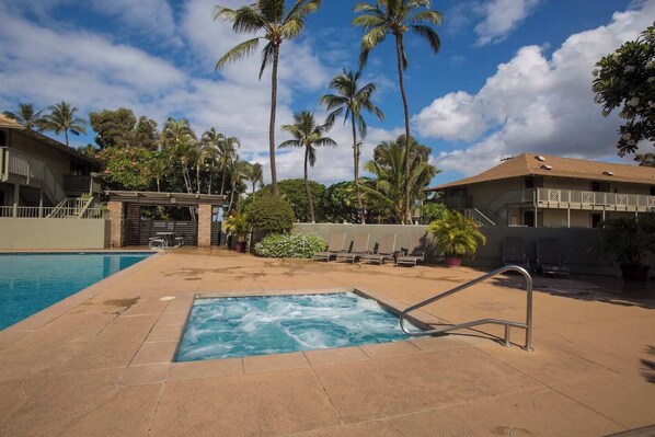 A swimming pool with a hot tub, surrounded by palm trees and lounge chairs, indicating a resort setting. - Kihei Bay Surf 227 by Maui Rental Group (Kihei)