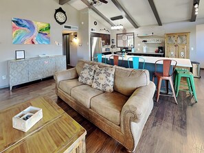 A modern living room with a beige sofa, a wooden coffee table, and a colorful abstract painting on the wall. - Valley View by Ruidoso Vacation Rentals (Ruidoso)