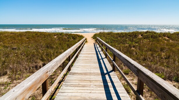 A wooden boardwalk leading to a beach with grassy dunes. - Summer Daze by Distinctive Beach Rentals (Palm Coast)