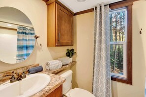 A bathroom with two sinks, a toilet, a mirror, and a window with a view of trees. - Stargazer Cottage | Hiking · Fire Pit · Internet (Mentone)