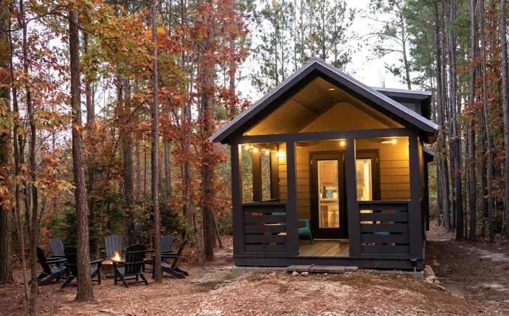Eine Hütte mit Veranda, umgeben von Bäumen.