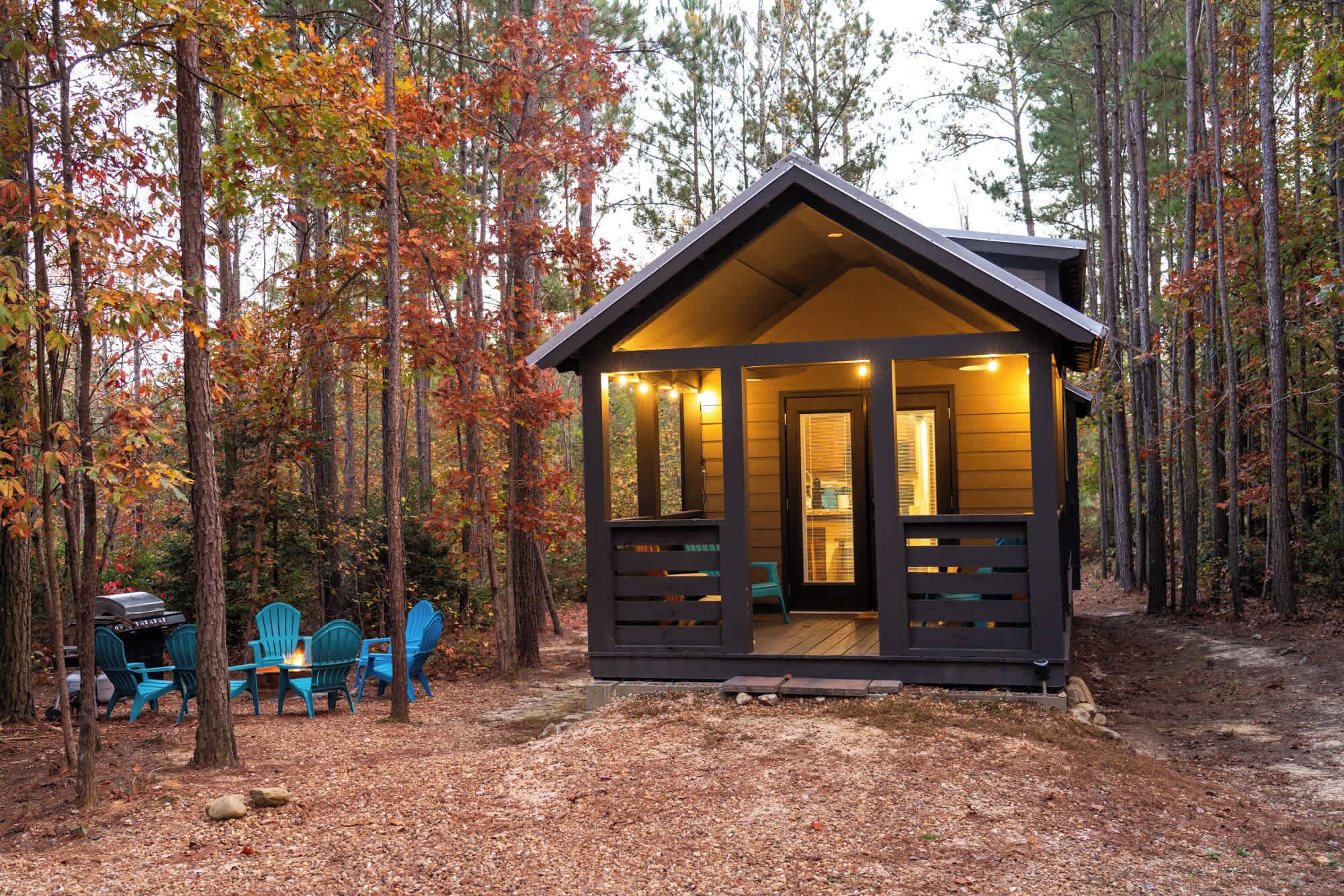 Eine Hütte mit Veranda, umgeben von Bäumen im Herbstlaub.