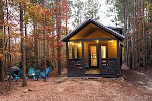 A cabin with a porch, surrounded by trees with autumn foliage. - Stargazer Cottage | Hiking · Fire Pit · Internet (Mentone)