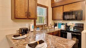 A kitchen with wooden cabinets, a granite countertop, a microwave, a stove, and a window with blinds. - Black Diamond at Mentone with Free Internet! Hikes (Mentone)