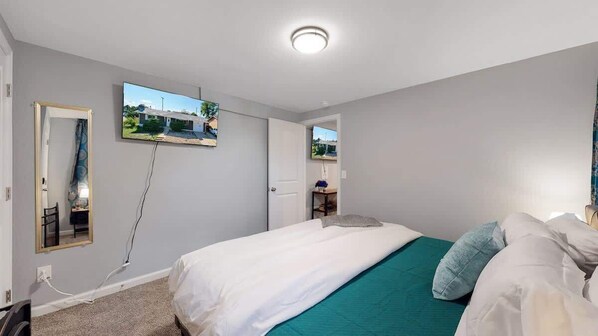 Une chambre à coucher avec un lit, un miroir et un téléviseur fixé au mur.