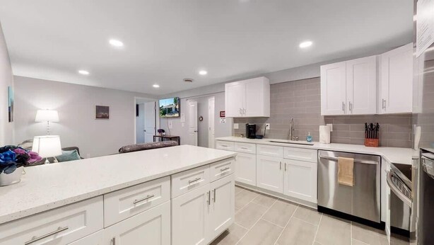 A modern kitchen with white cabinets, stainless steel appliances, and a tiled backsplash. - Spacious Lower Unit Updated Two King Beds in Denver (Denver)