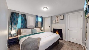 A bedroom with a bed, nightstands, a fireplace, and curtains. - Spacious Lower Unit Updated Two King Beds in Denver (Denver)