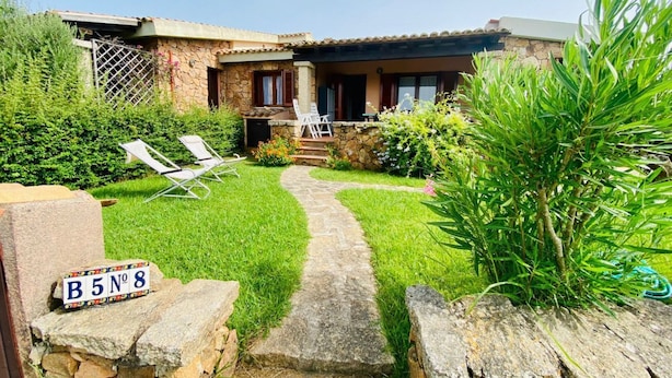 Una casa in pietra con un vialetto che conduce a una zona relax con due sedie.