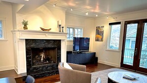 A living room with a fireplace, comfortable seating, a television, and a view of the outside. - Luxury home; king ensuites, walk to lifts/main st (Park City)