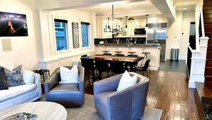 A modern living room with a sofa, two armchairs, a coffee table, and a kitchen area with a dining table and bar stools. - Luxury home; king ensuites, walk to lifts/main st (Park City)