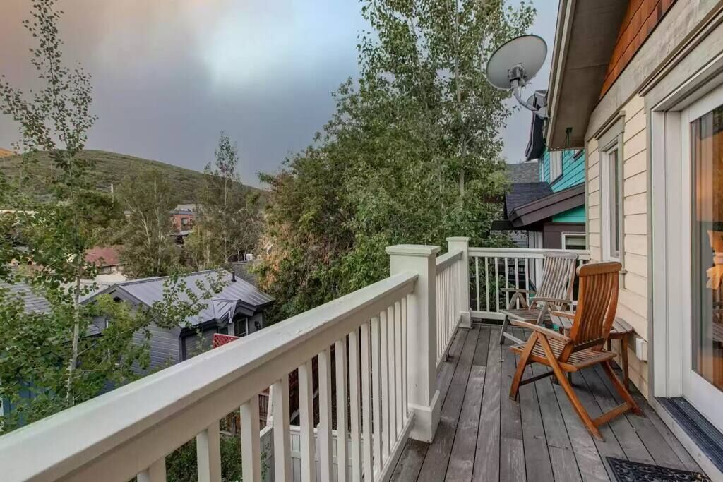 A wooden deck with a white railing, a satellite dish, and a chair.