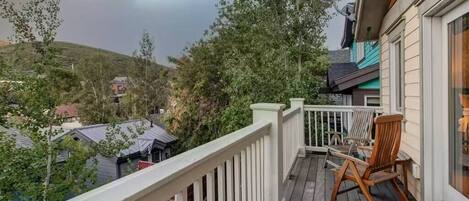 A wooden deck with a white railing, a satellite dish, and a chair.